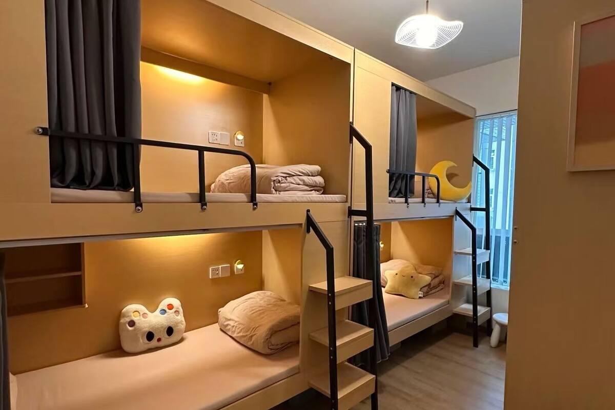 A bunk bed room with a staircase, a small window, and a wall-mounted light fixture.