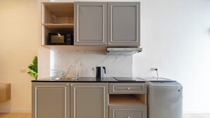 Una cucina moderna con mobili grigi, un piano di lavoro nero, un forno a microonde integrato, un bollitore e una lavatrice.