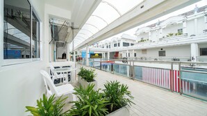 Il ponte di una nave da crociera con piante in vasi, una ringhiera bianca e vista dell'architettura della nave.
