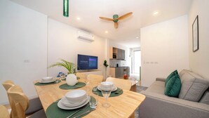 Un soggiorno moderno con zona pranzo, un divano grigio e una ventola a soffitto.