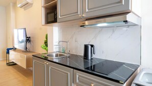 Una cucina moderna con un piano di lavoro nero, elettrodomestici in acciaio inossidabile e una parete di fondo in marmo.