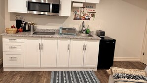 A kitchen with white cabinets, a stainless steel microwave, a toaster, and a coffee maker. - 1 bedroom in-home mini apartment in Dieppe 5 min drive to the airport WIFI (Dieppe)
