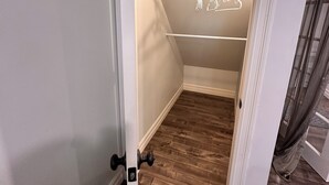 A walk-in closet with wooden flooring, a white door, and a hanging rod. - 1 bedroom in-home mini apartment in Dieppe 5 min drive to the airport WIFI (Dieppe)