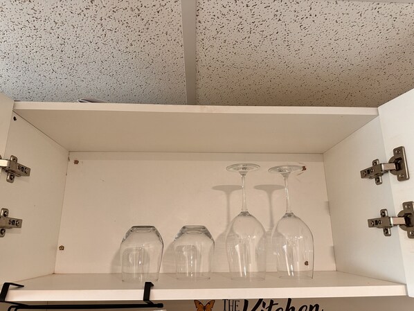 A white cabinet with a speckled ceiling, containing three wine glasses and two empty glass jars. - 1 bedroom in-home mini apartment in Dieppe 5 min drive to the airport WIFI (Dieppe)