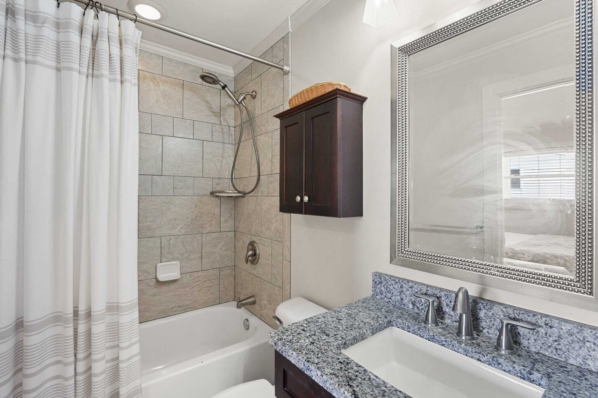 Un baño moderno con ducha, bañera, tocador y un espejo grande.
