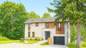 A modern two-story house with a stone facade, a black garage door, and a well-maintained lawn.