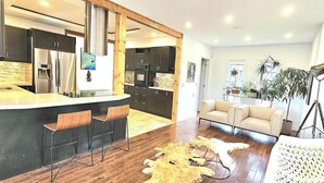A modern kitchen with dark cabinets, a stainless steel refrigerator, and a bar area with stools.