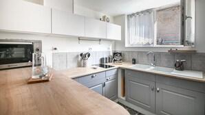 Une cuisine moderne équipée d’un four à micro-ondes, d’un évier et d’un plan de travail en bois.