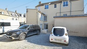 Un espace de stationnement où sont garés un SUV noir et une petite voiture blanche.