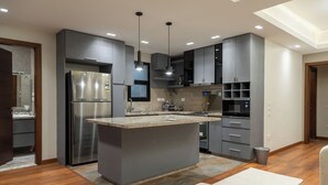 Una cocina moderna con una isla central, electrodomésticos de acero inoxidable y armarios oscuros.