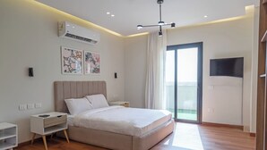 Un dormitorio moderno con una cama grande, un televisor de pantalla plana y un balcón con vistas.