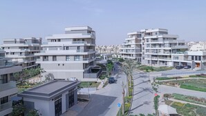 Un complejo residencial moderno con varios edificios, un camino peatonal central y zonas ajardinadas.