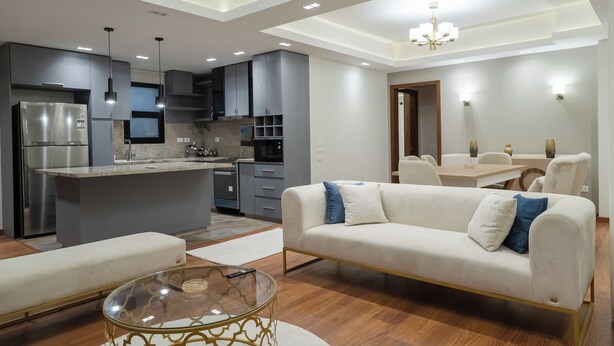 Una sala moderna con un sofá, una mesa de centro de cristal y un comedor con una mesa y sillas.