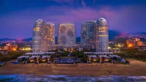 A beachfront hotel with three prominent curved buildings, a sandy beach, and a view of the ocean.