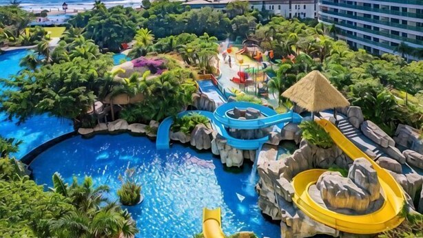 A resort with a large pool, water slides, and lush greenery.