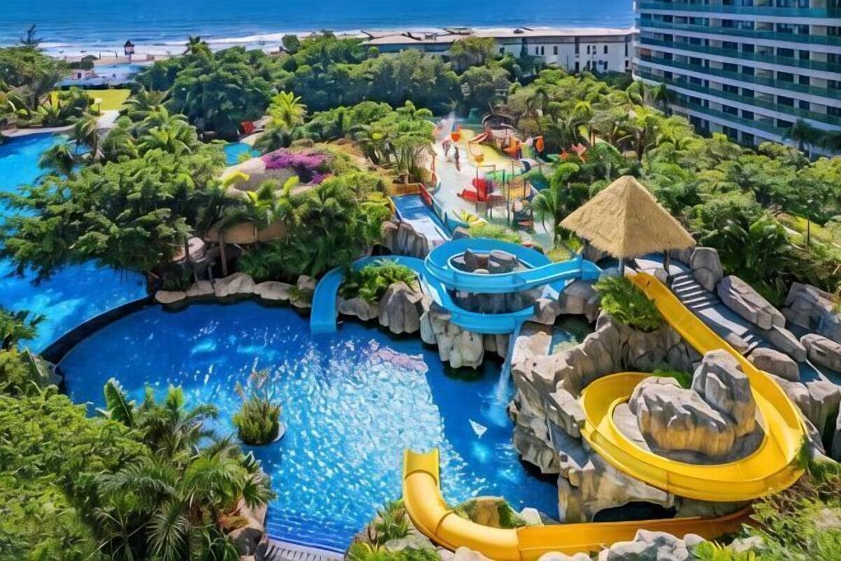 A resort with a large pool, water slides, and lush greenery.