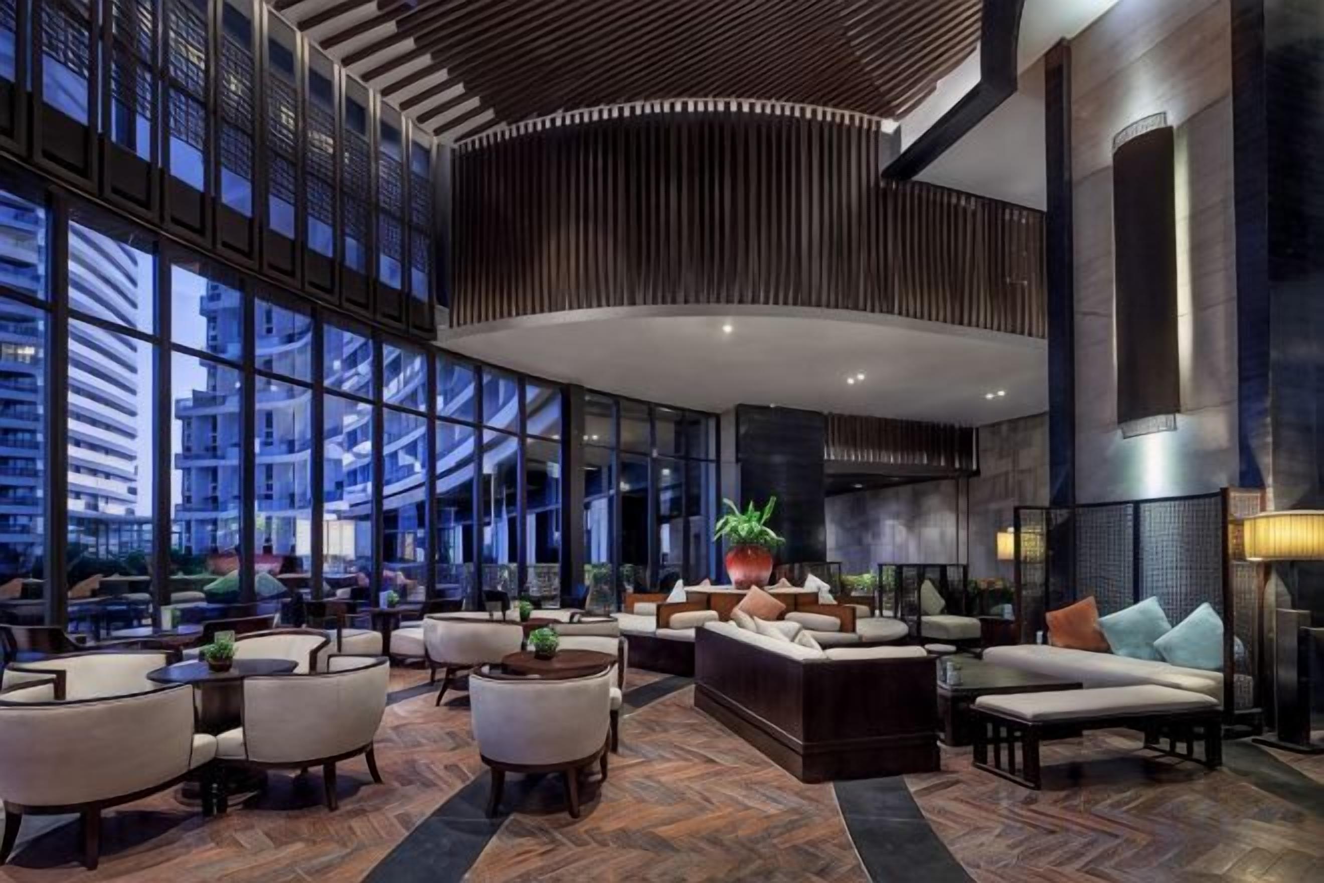 A spacious lobby with a high ceiling, large windows, and modern furniture.