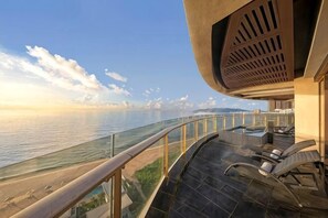 A balcony with a view of the sea, a pool, and lounge chairs. - Howard Johnson Sandalwoods Resort Shuangyue Bay Huidong Huizhou (Huidong)