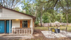A single-story house with a covered porch, a fenced backyard, and a patio area with outdoor furniture. - Cozy duplex w/fire pit & BBQ (Pensacola)