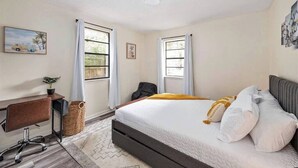 A bedroom with a bed, desk, chair, and two windows with curtains. - Cozy duplex w/fire pit & BBQ (Pensacola)