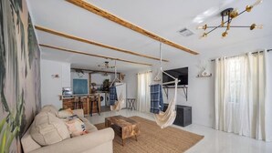 Uma sala de estar com sofá, mesa de centro, rede e televisão.