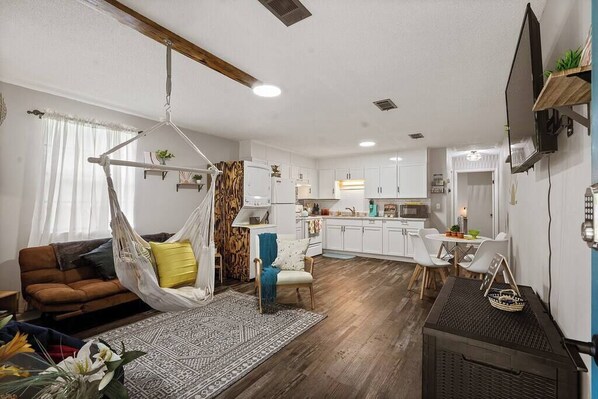 Un espacio habitable moderno con una hamaca, un comedor y una cocina.