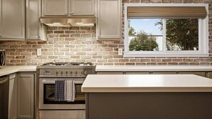 Una cocina con pared de ladrillo, electrodomésticos de acero inoxidable y ventana con vistas.