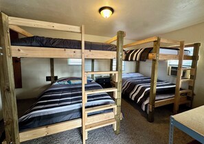 Una camera con un letto a castello, un tavolino e una lampada a soffitto.