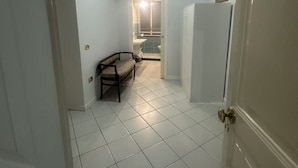 A narrow hallway with white tiled floors, a bench, and a door leading to another room. - Rooms for Vacation and Relaxation. City Center SORRENTO Coast (Vico Equense)