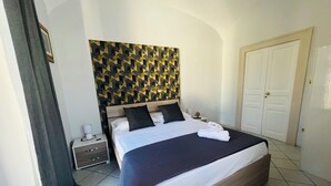 A hotel room with a bed, a nightstand, a wall with a geometric pattern, and a door. - Rooms for Vacation and Relaxation. City Center SORRENTO Coast (Vico Equense)