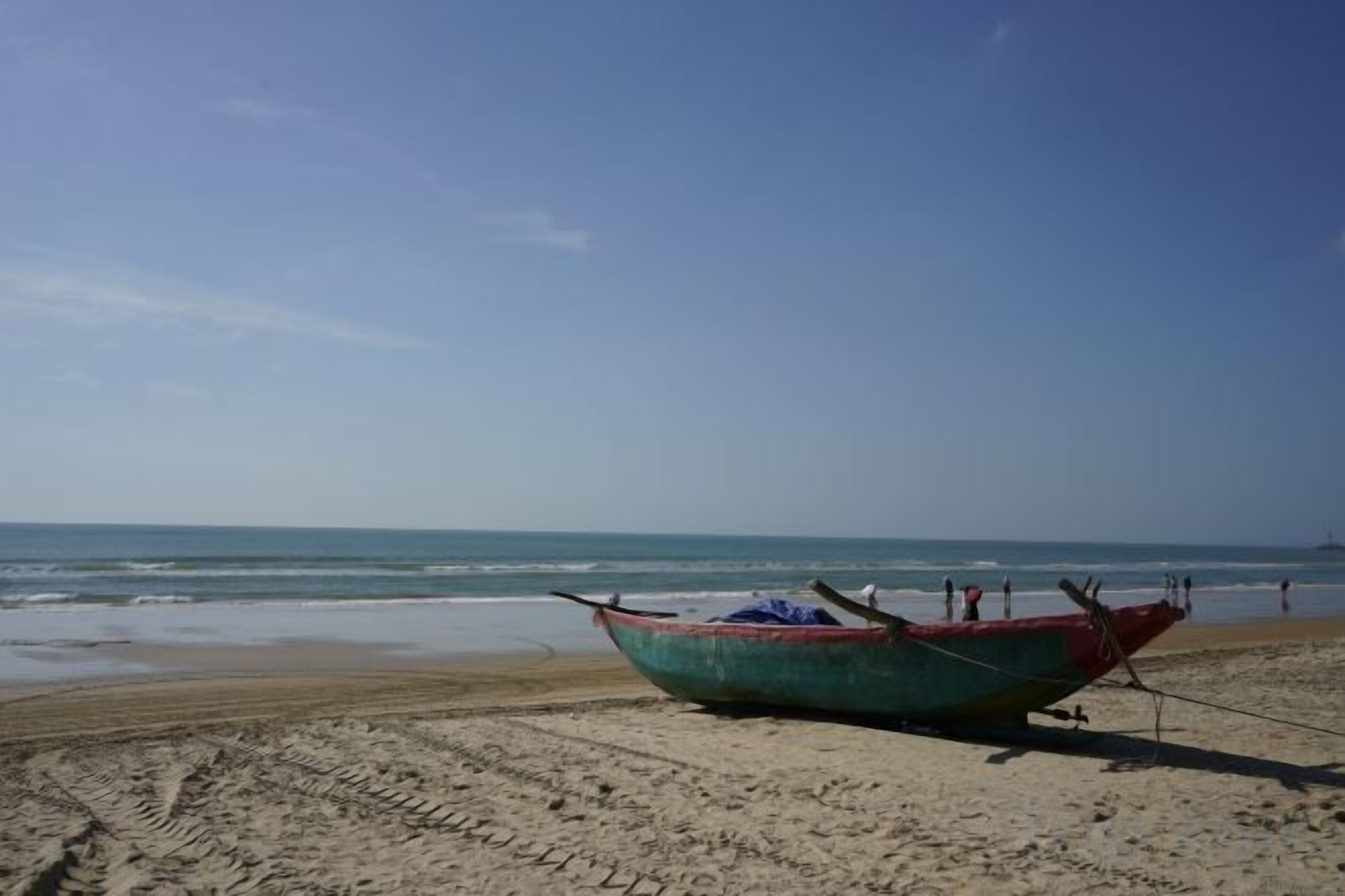 Un bote sobre una playa arenosa, con el océano al fondo.
