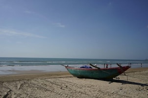 Un bote sobre una playa arenosa, con el océano al fondo.
