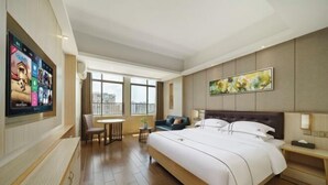 A hotel room with a large bed, a TV mounted on the wall, a dining table, and a sofa. - Kaiwei Hotel (Wanning High-speed Railway Station Branch) (Wanning)