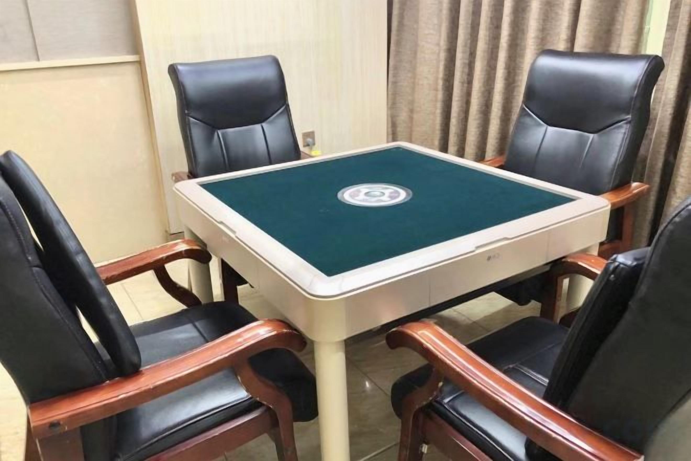 Una habitación con una mesa de billar verde, cuatro sillas de cuero negro y una mesa de madera.