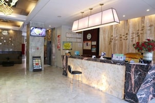 A hotel reception area with a marble counter, a television screen, and a clock on the wall.