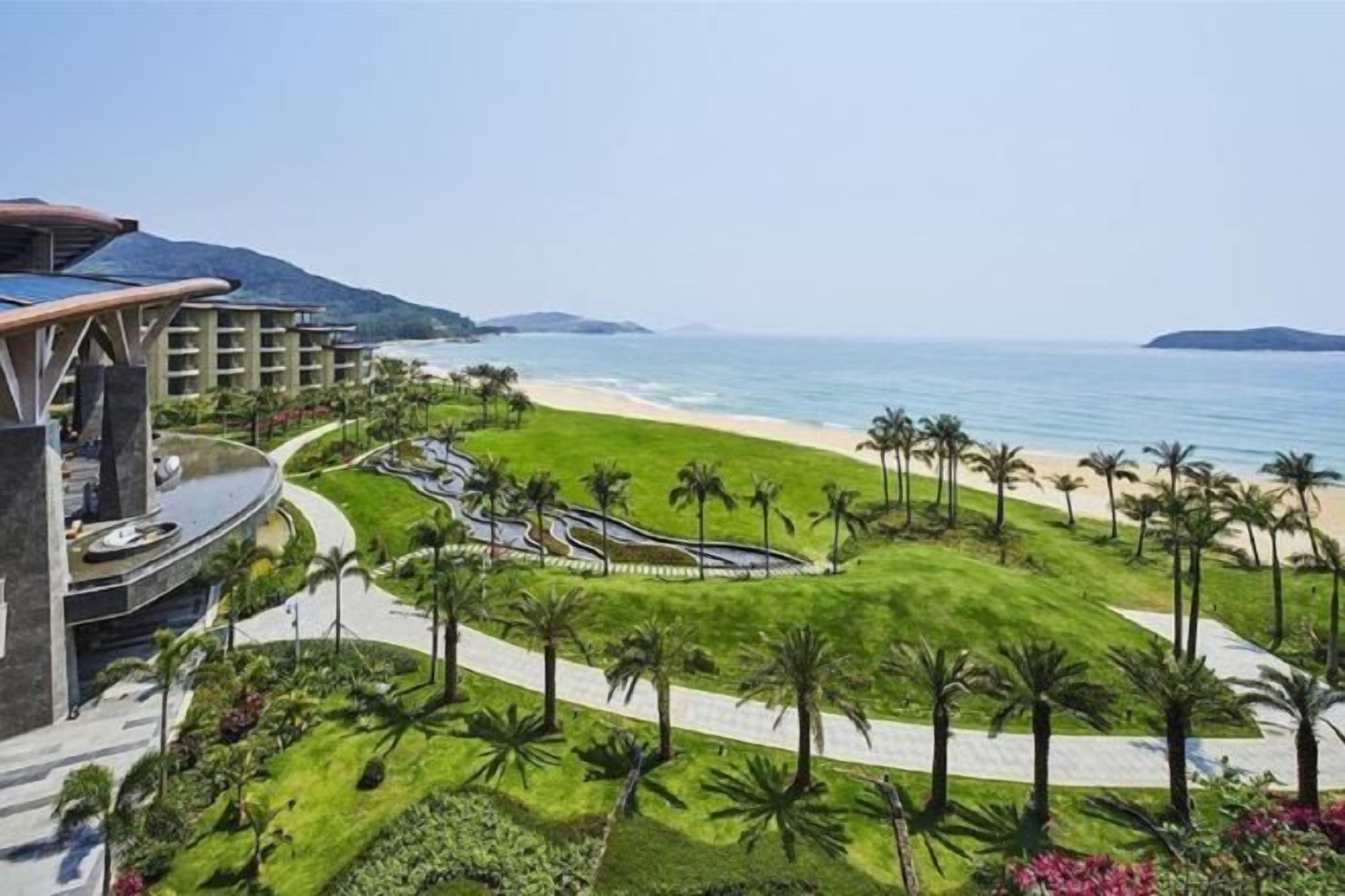 A resort with a beach view, palm trees, and a landscaped area.