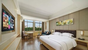 A hotel room with a large bed, a TV mounted on the wall, a dining table, and a view of the outdoors. - Kaiwei Hotel (Wanning High-speed Railway Station Branch) (Wanning)