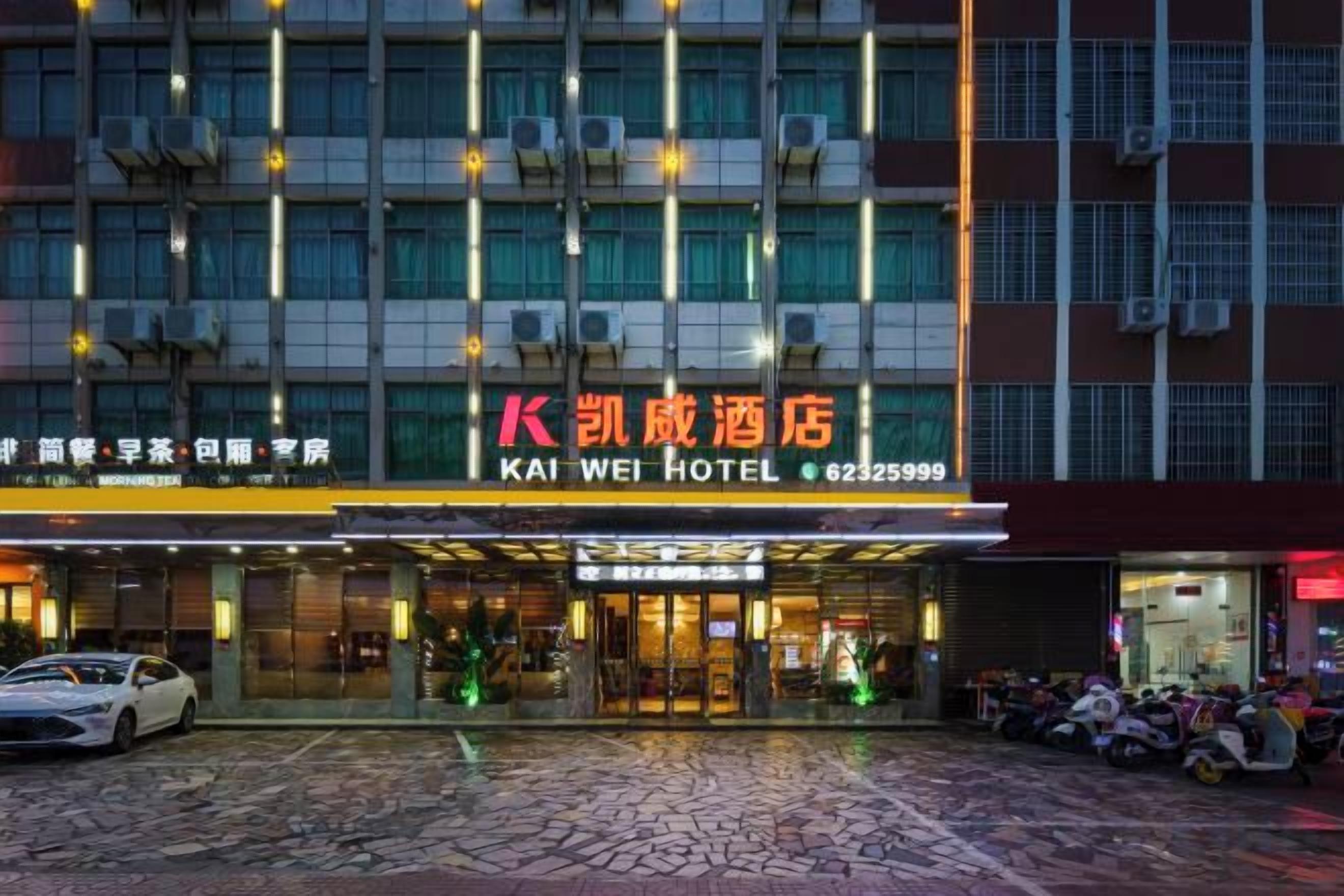 A hotel entrance with a sign reading 'KAI WEI HOTEL' and a contact number.
