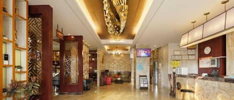 A hotel lobby with a reception desk, seating area, and decorative elements.