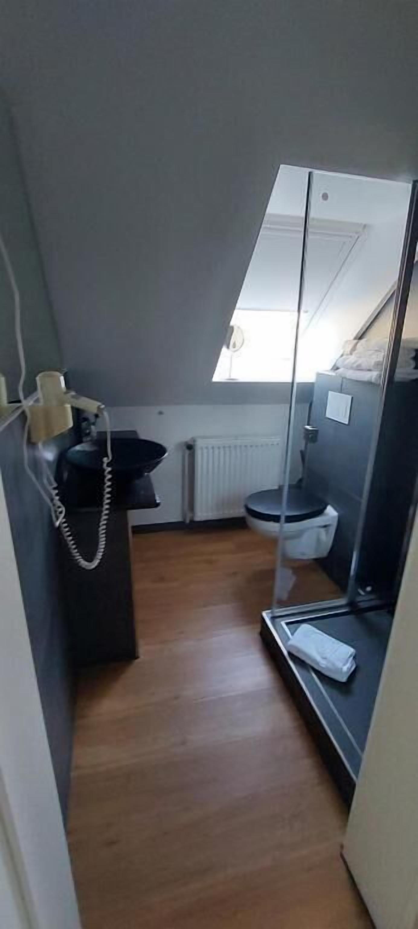 Um banheiro compacto e moderno, com box de chuveiro, vaso sanitário e pia pequena.