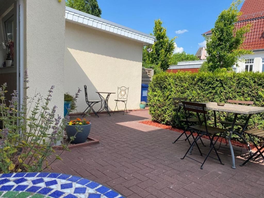 A patio with a table and chairs, a potted plant, and a small garden area.