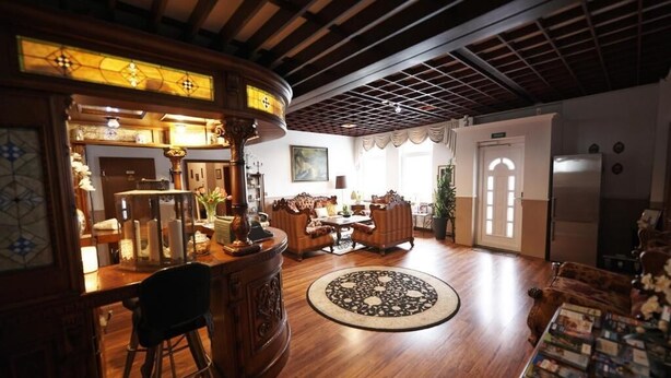 A spacious living room with a wooden floor, a round patterned rug, and a dining area with a table and chairs. - Hotel Wurster Kroog (Bremerhaven)