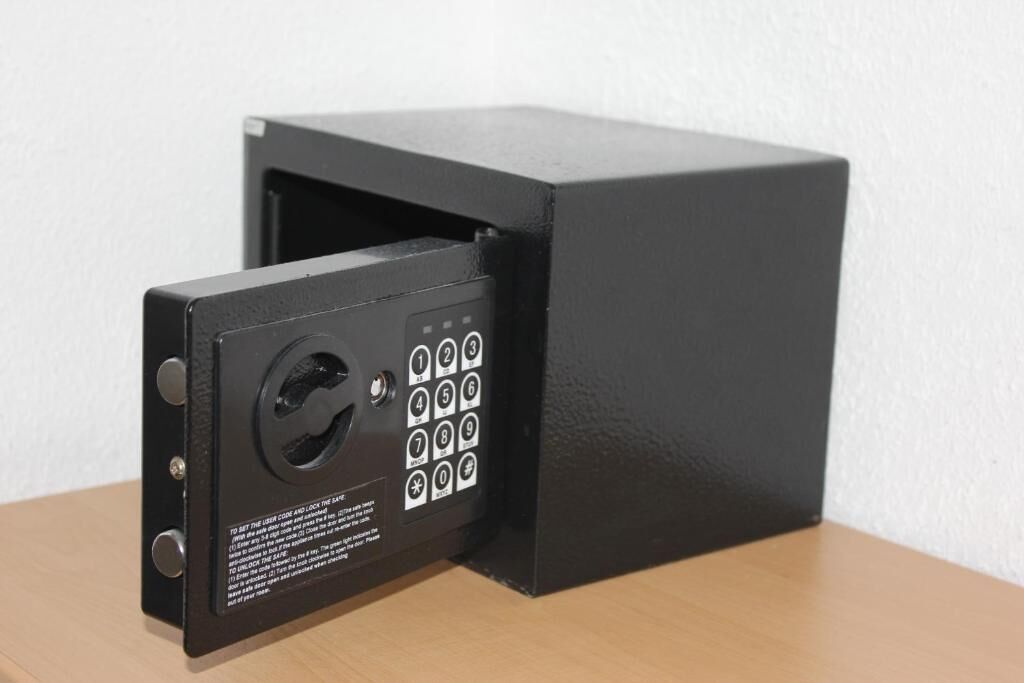 A black security keypad with a numeric keypad and a keyhole, mounted on a wooden surface.