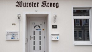 A building entrance with a sign reading "Wuster Kloog" and a door with a sign above it. - Hotel Wurster Kroog (Bremerhaven)