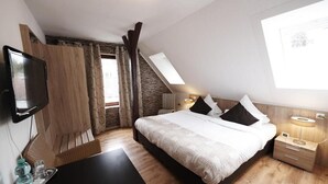 A modern bedroom with a large bed, a TV, a desk, and a window with a view of the outdoors. - Hotel Wurster Kroog (Bremerhaven)