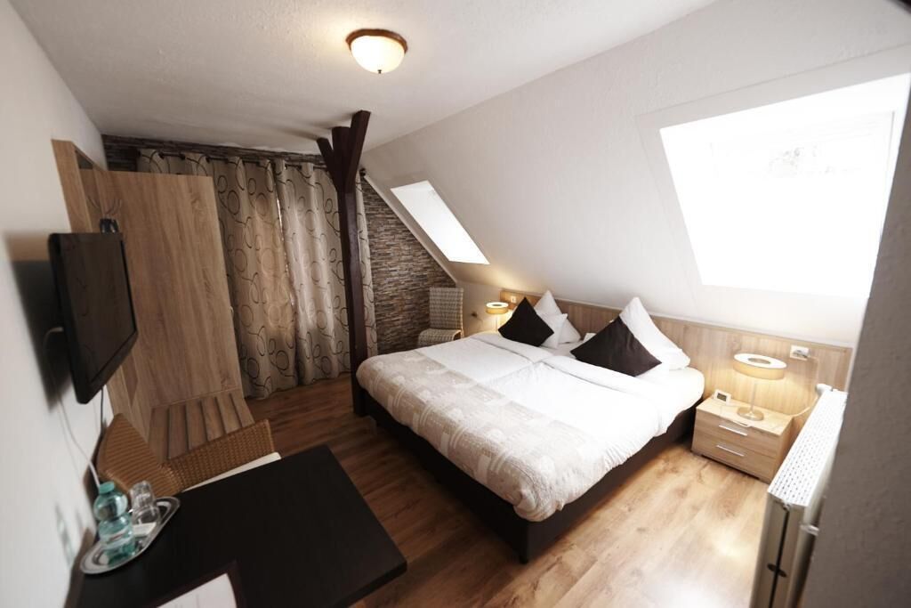 Een slaapkamer met een bed, nachtkastjes, een televisie, een raam en een trap.