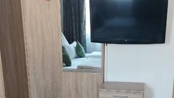 Un dormitorio con una cama, un armario de madera, un televisor y una mesita.