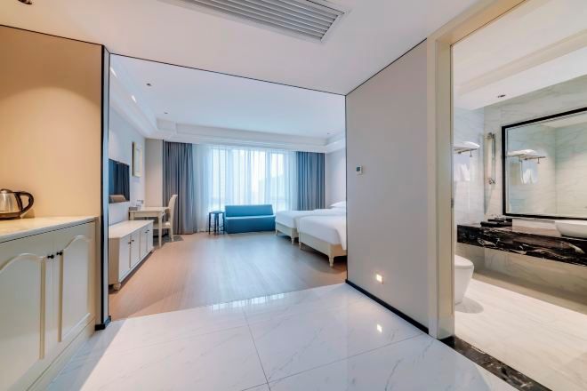 Una habitación de hotel con una cama, un escritorio, una silla, una mesita y un espejo.