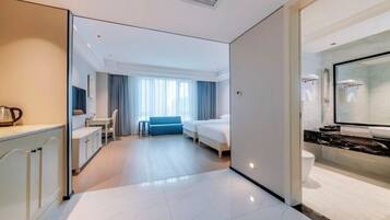 Una habitación de hotel con una cama, un escritorio, una silla, una mesita y un espejo.