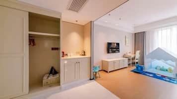 A hotel room with a closet, a small kitchenette, a television, and a window with a view.